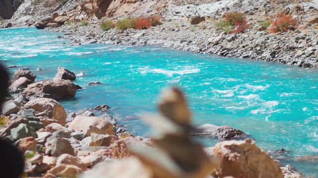 Beautiful blue river flowing in the Himalayas. Defocused stone tower near flowing Zanskar River in Ladakh, India. River seen from Phugtal monastery. Nature, environment and climate change concept.