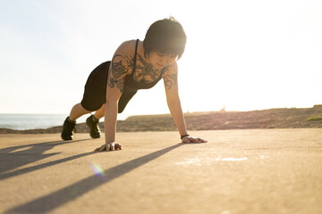Woman exercising plank pose outdoors at sunset