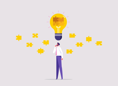 Symbolizing creative thinking and strategic problem solving, businessman analyzing floating puzzle pieces around glowing lightbulb