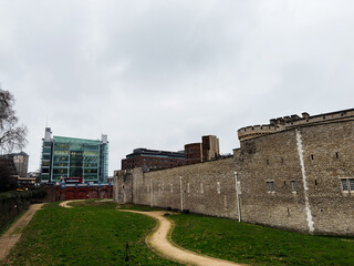 Tower of London historic castle wall beside modern glass office building with winding grassy path in London, UK © AS Photo Family