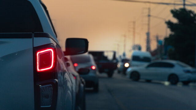 Abstract rear side of pickup car with turn on brake light. Driving on a congested rural road. Environment in the evening sky. With silhouette of electic pole and trees.