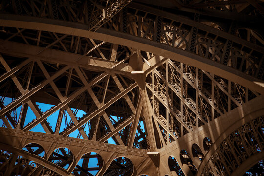 Eiffel Tower structural detail: Abstract close-up of iron lattice framework and rivets beneath the Eiffel Tower at dusk, Paris, France 