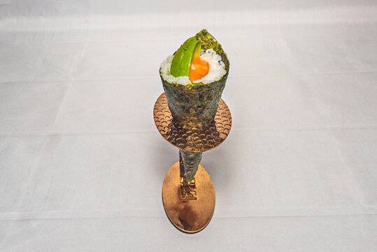 A composition of eight temaki rolls arranged in two rows, showcasing a variety of fillings: raw salmon, bluefin tuna