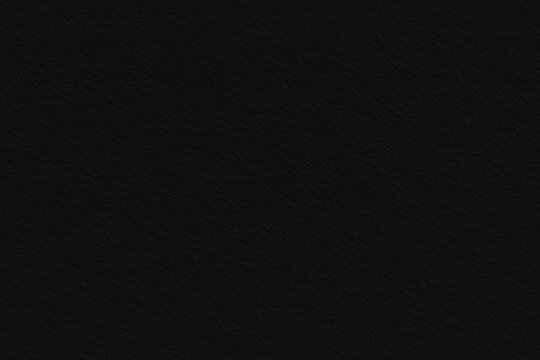 A textured black background with a subtle grainy texture. The black background is ideal for sleek, modern designs. Paper texture. Black background with copy space.