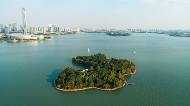 Expansive Jinji Lake in Suzhou with a verdant island, graceful sailboats, and modern city architecture
