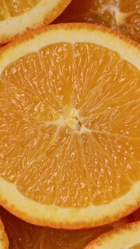 Orange slices slowly rotate around a central citrus half in a macro video. Glistening juicy segments fill the frame. Perfect looping background for food, wellness and branding.