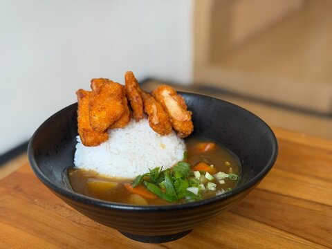 Japanese chicken katsu curry served in a black bowl with crispy breaded chicken cutlet and thick, rich curry sauce over rice. A hearty and satisfying comfort food dish. April 1, 2026 - BSD, Indonesia