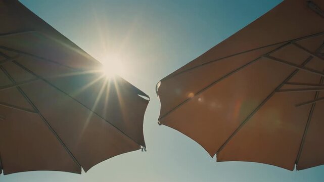 Sunlight peeking through two beach umbrellas on a bright summer day creating a warm and inviting atmosphere. 4k Footage Video
