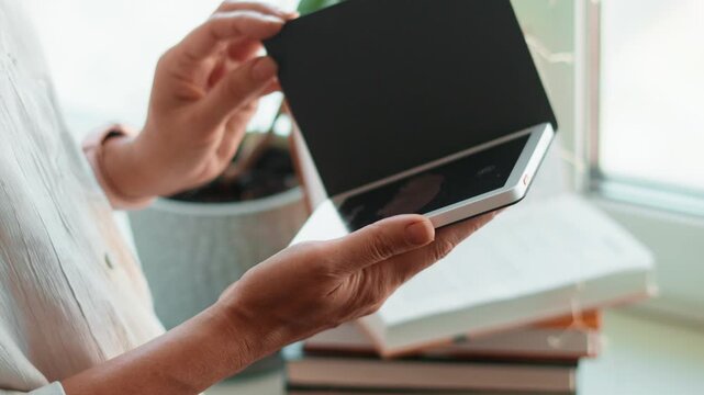 Person holding tablet and reading ebook at home. Digital reading, modern technology and cozy lifestyle with books, soft light and comfortable environment for learning and relaxation