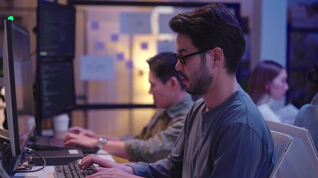 Focused man writing computer code and developing applications during a late-night work session.