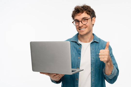 Smiling Caucasian man in eyeglasses freelancer IT Programmer hold laptop computer with thumb up using application, browsing sites, shopping in internet, app, reading website on white studio background