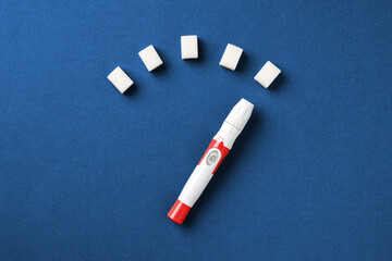 Blood glucose meter with sugar cubes on blue background diabetes concept