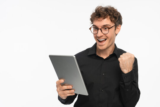 Young businessman with tablet showing winner emotion isolated on white studio background, success, achievement, victory, business growth and digital work concept
