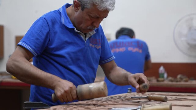Footage of a skilled craftsman carving wood using a chisel and mallet. Highlights traditional techniques, intricate patterns, and authentic workshop environment with detailed craftsmanship.