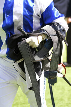 Jockey con silla, l&aacute;tigo, estribos y cincha en hip&oacute;dromo