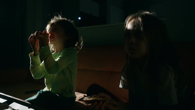 Two boys eating snacks on the sofa during a movie