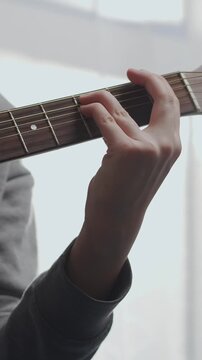 Close-up sequence of a person practicing gentle acoustic guitar playing indoors, focusing on the wooden fretboard, strings, and relaxed hands in soft natural light