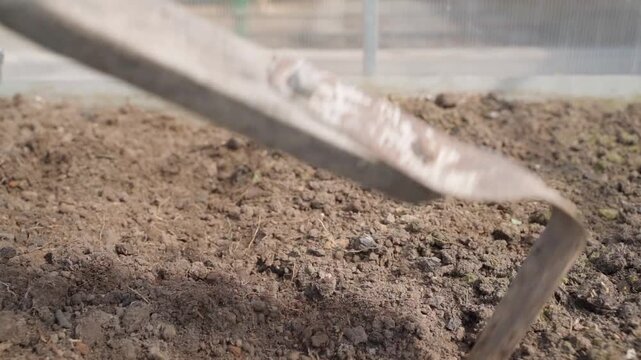 Close-up of digging soil in greenhouse with hoe