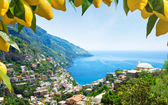 Picturesque view of Positano on Amalfi Coast, Italy, with colorful hillside houses overlooking Mediterranean Sea. Bright yellow lemons in foreground. Welcome to Positano concept 