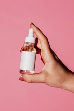 Hand holding skincare serum bottle