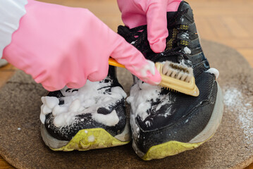 Man carefully cleaning dirty sneakers with brush and soap foam. Cleaning dirty sneaker upper with stiff brush