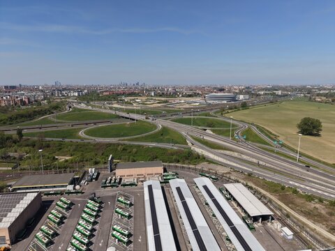 Drone view of San Donato Milanese depot with electric buses and rooftop solar panels. Daylight shot highlights green urban transport and sustainable infrastructure in Milan.