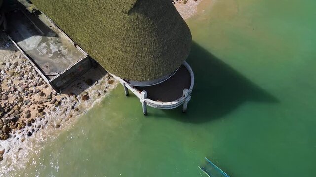 Aerial view of thatched roof structure over coastal water