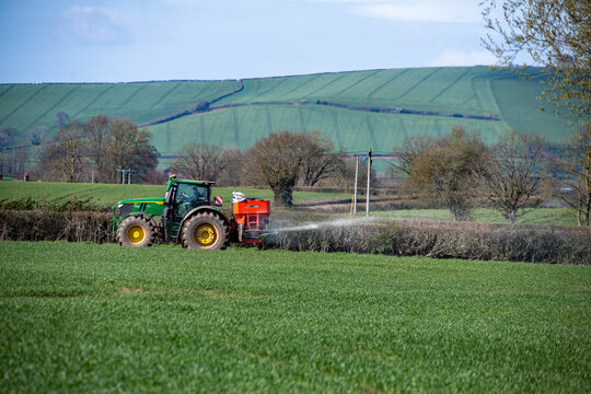 Exeter, Devon, uk. 04 01 26. A tractor with a fertiliser spreader working in a green field. Food production, farming and agriculture picture. Crops and food production. 