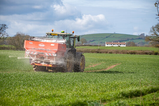 Exeter, Devon, uk. 04 01 26. A tractor with a fertiliser spreader working in a green field. Food production, farming and agriculture picture. Crops and food production. 