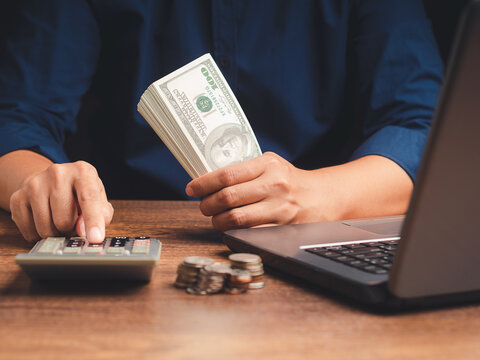 Counting cash while using calculator at desk