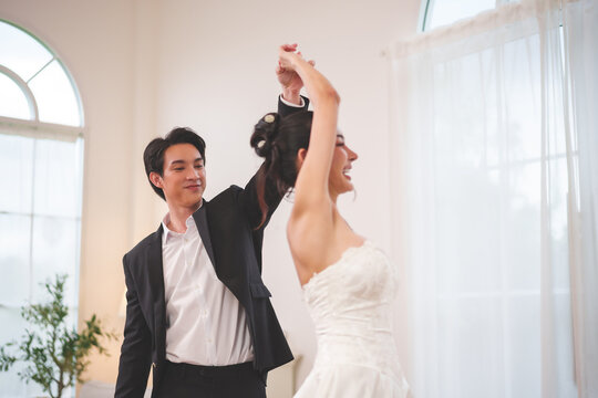 Happy wedding couple dancing together and laughing during celebration