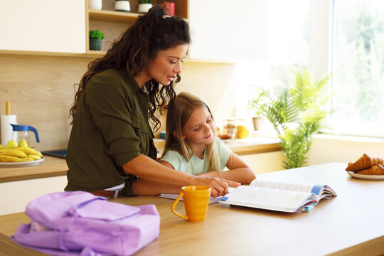 Mother helping daughter with homework in kitchen