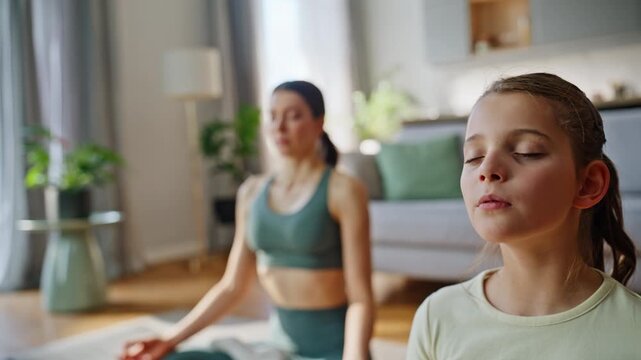 Closeup meditating mom child in room. Serene aunt kid practicing yoga together