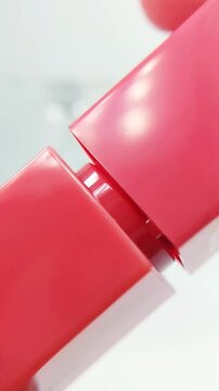 Process of opening a lip tint cap. Close up view focusing on the cap with soft blurred white background. Makeup product, beauty tool, cosmetic packaging detail.