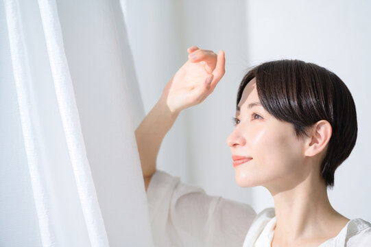 窓からの日差しを浴びる日本人女性