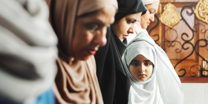 A group of Muslim women, including a young girl, wearing hijabs in various colors. The Muslim women reflect a sense of community and spirituality, showcasing their cultural identity.