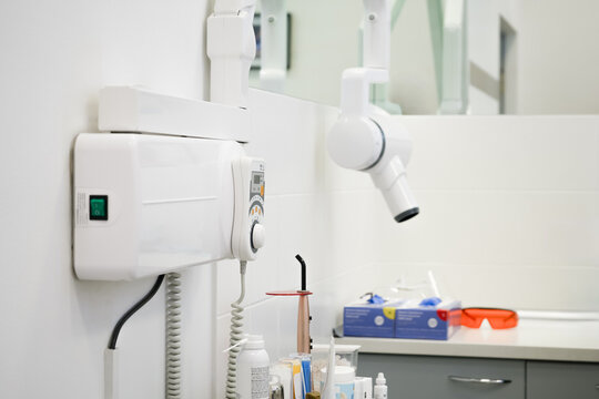 Wall mounted dental x-ray unit with digital control panel for diagnostics. Professional medical equipment for teeth imaging and radiology in modern clinical cabinet.