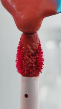 Process of pouring red lip tint liquid onto the brush tip, flowing slowly. Isolated on white background, close up view, makeup application concept with glossy texture.