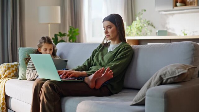 Modern family typing computers resting at couch. Mother daughter texting devices