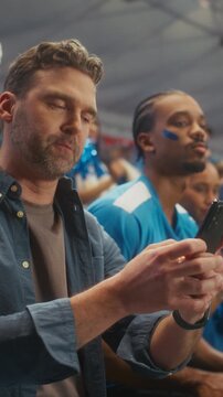 Vertical Screen. Sport Stadium Fans. Diverse Supporters Watch a Decisive Soccer Championship Moment on a Smartphone, Then Erupt in Joy, Cheering in a Packed Arena at an International League Match.