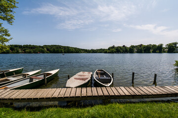 Rowing boats moored at a wooden pier on the calm water of Wesslinger See in Bavaria, Germany  © Stephan