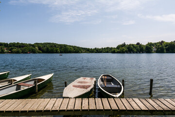 Rowing boats moored at a wooden pier on the calm water of Wesslinger See in Bavaria, Germany  © Stephan