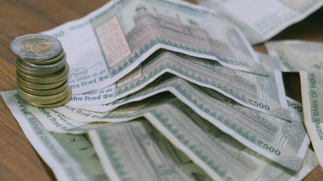 High angle view of Indian five hundred rupee notes and stacked coins