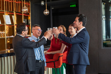 Group of diverse business professionals celebrating success and teamwork with a cheerful toast in a modern office lounge. Concept of achievement, partnership, and corporate happiness.