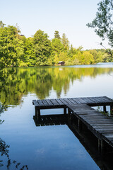Fototapeta premium Wooden pier overlooking the calm water of Wesslinger See lake in Bavaria, Germany