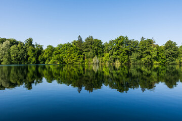 Fototapeta premium Wooden pier overlooking the calm water of Wesslinger See lake in Bavaria, Germany