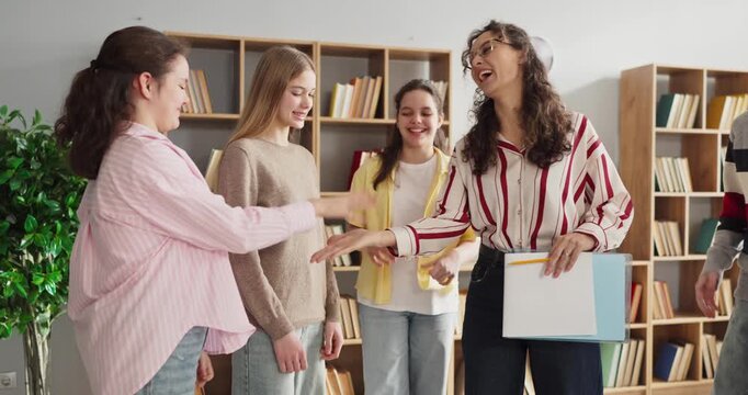 Teacher counselor with teenagers in support group. Students share feelings in a classroom during therapy discussion and meeting, building trust and skills. Focus on student wellbeing support.
