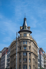 Fototapeta premium Historic ornate corner building with tower and elegant facade against blue sky in Barcelona city architecture