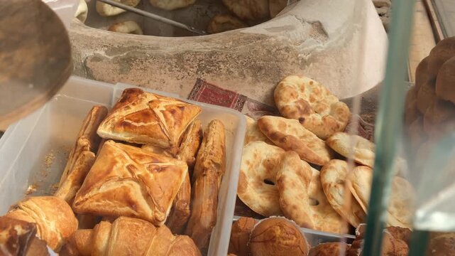 Selling hot bread. Baker sells hot traditional pita baked in stone tandoor. Round flatbread. Middle Eastern bakery in local shop. Abundance of bread varieties in Middle East and Caucasus