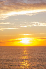 Fototapeta premium Golden sunset over calm ocean horizon with warm sky and copy space